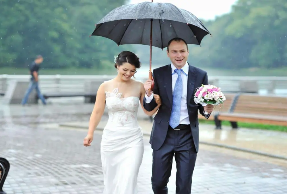 newly wed couple under an umbrella on their wedding day