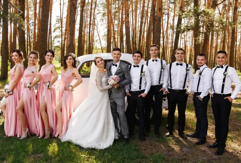 Bride, bridesmaids, groom and groomsmen holding bouquet, corsages, and boutonnieres respectively